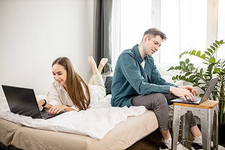 couple on bed on laptops